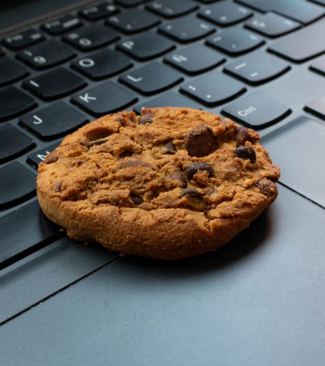 Ein Keks liegt auf einer Tastatur als Symbol für Cookies